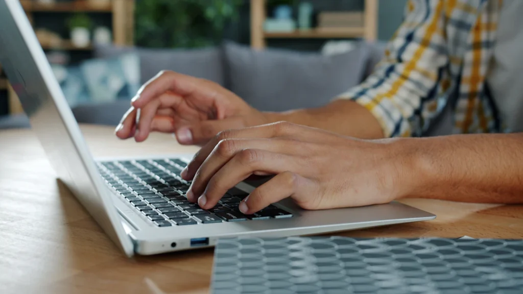 Person typing on a laptop at a desk to complain about an NDIS plan manager