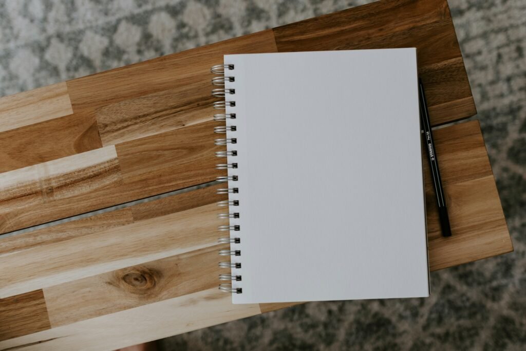 A blank spiral notepad and pencil on a wooden desk, representing the NDIS access request form