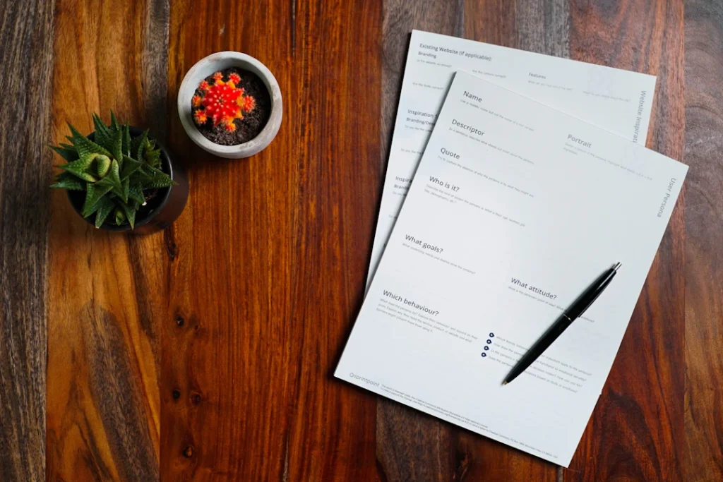 Papers and a pen on a wooden table for preparing an invoice that meets NDIS invoice requirements