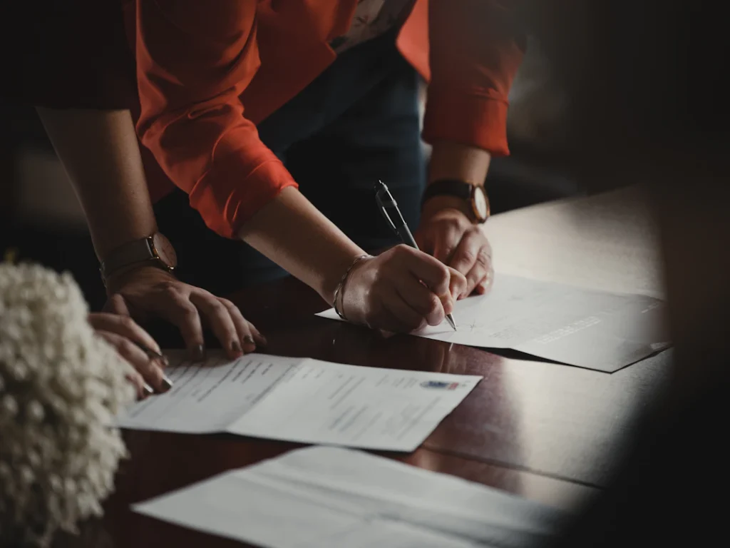 Person signing documents at a table before agreeing to an NDIS service agreement