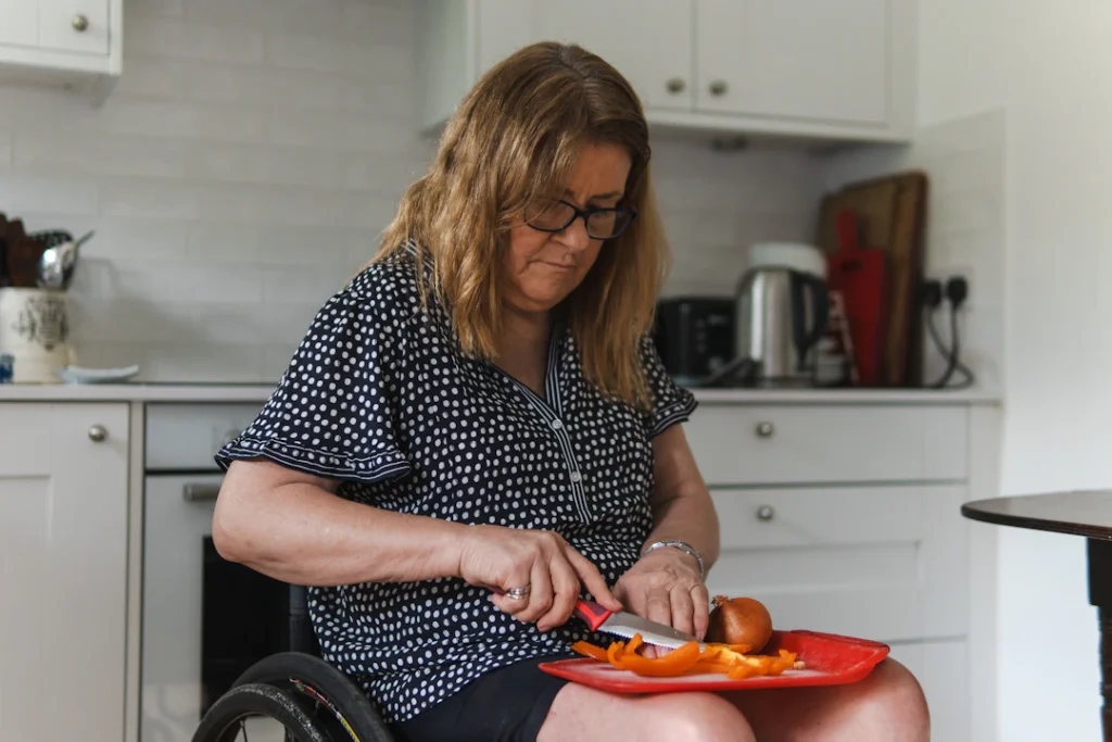 Woman using a wheelchair preparing food independently in her kitchen, an example of occupational therapy supporting daily living skills